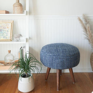 Handwoven Luxe Indigo Oversized Stool in a living room besides of a small plant.