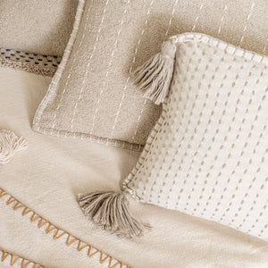 Hand Quilted Striped Cotton Pillow and Hand Quilted Tassel Cotton Throw Pillow on a beige bed.