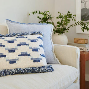 Indigo Blue Geometric Boho Throw Pillow With Fringe on a cream color sofa.