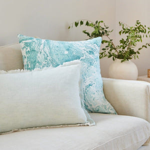 Turquoise Marbled Linen Decor Pillow on a cream color sofa in a living room.