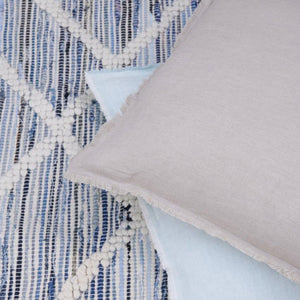 Beige Soft Linen Throw Pillow on an Recycled Denim Handwoven Rug.