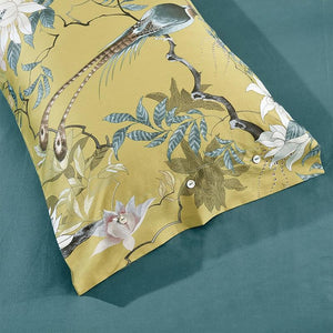 Yellow pillow cover with animals printed made of egyptian cotton on a green bed sheet.