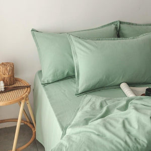 Pillow covers in green color; flat bedding sheet can be seen as well.