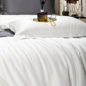White comforter and white pillow cover with a tray and a necklace. 
