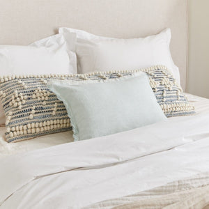 Handwoven Recycled Denim Pillow on a bed dress with a white bedding set.