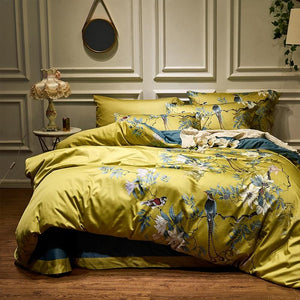 Yellow birds printed queen king duvet cover set made of Egyptian Cotton with pillow covers in a bedroom with a bedside table lamp on a wooden floor.