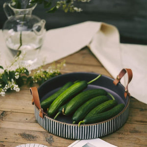Vegetables on a stripped ceramic plate with leather handles.