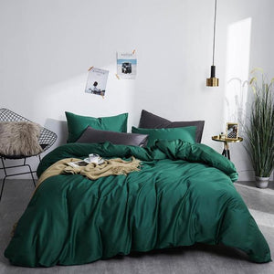 Front view of Grace Silk Green Duvet Cover Set in minimalist bedroom. The bedding set comes with two pillowcases, the duvet cover, and the flat bed sheet.