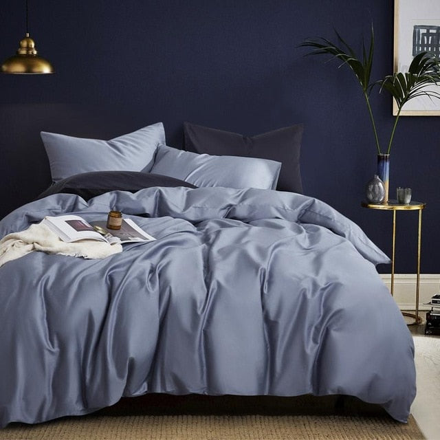 Front view of Florentine Silk Blue Duvet Cover Set in minimalist bedroom. The bedding set comes with two pillowcases, the duvet cover, and the flat bed sheet.