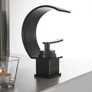 Black curved Gisela bathroom sink faucet with a transparent glass with candle.