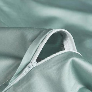 Green sheets close up with white zipper.