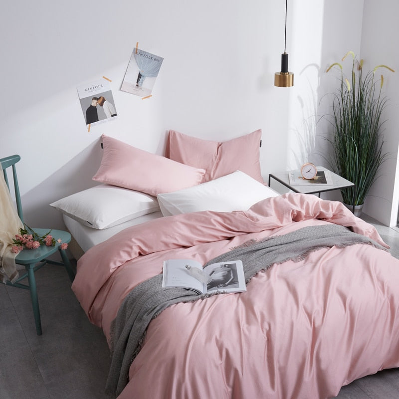 Front view of Flamingo Silk Pink Duvet Cover Set in minimalist bedroom. The pink bedding set comes with two pillowcases, the duvet cover, and the flat bed sheet.