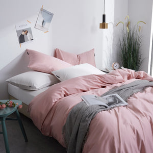 Corner view of Flamingo Silk Pink Duvet Cover Set in minimalist bedroom. The pink bedding set comes with two pillowcases, the duvet cover, and the flat bed sheet.