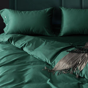 close up green venetia duvet cover set with two green pillow covers and some eucalyptus.