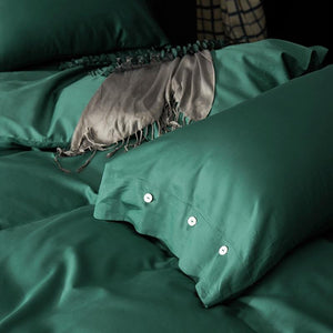green pillow cover with three buttons on a comforter