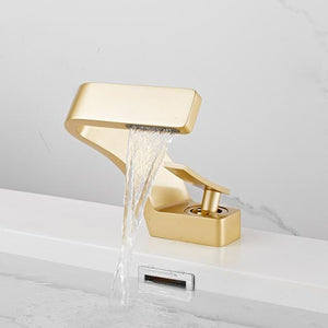 Gold Color Open Alpha bathroom faucet on a white sink.