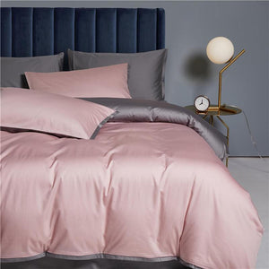 Ava Reversible Duvet Cover Set made of Egyptian Cotton in Gray and Quartz color. Clock and lamp on a bedside table.