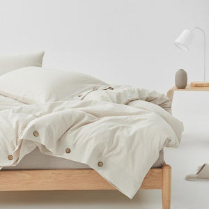 Duvet with buttons on a wooden bed.